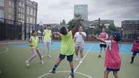 Six children play with a ball on a court with a coach.