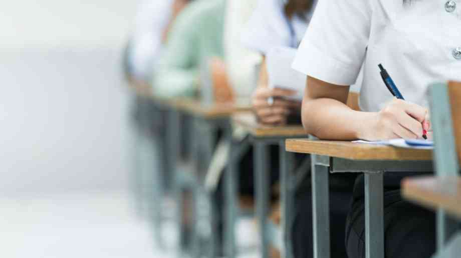 Students take exams in exam hall.