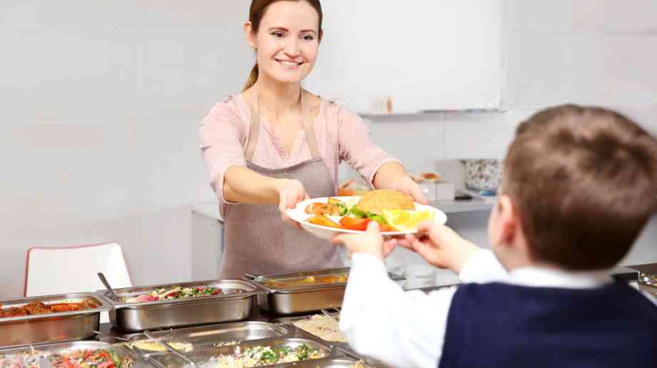 Dinner lady giving student a school dinner.