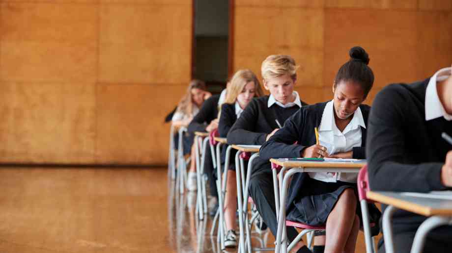 Children sit an exam in an exam hall.