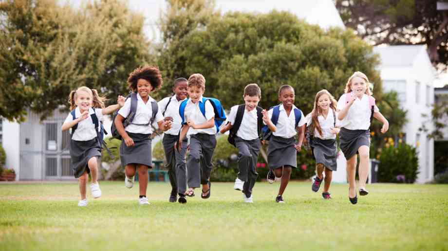 Primary school children run across a field.