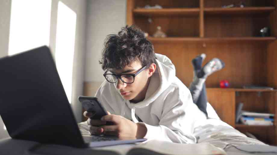 Teenage boy using smartphone while studying