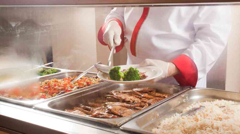 Chef serving up a plate of food at a school