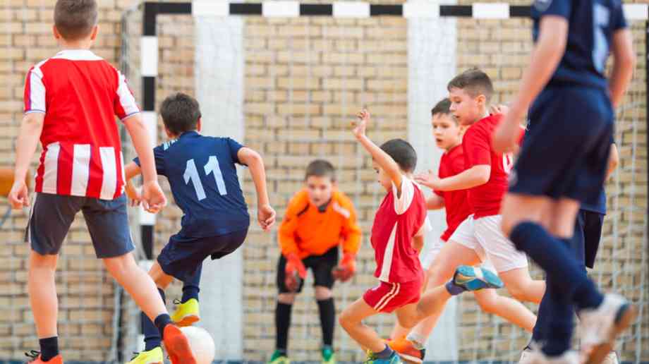 Children playing football inside.